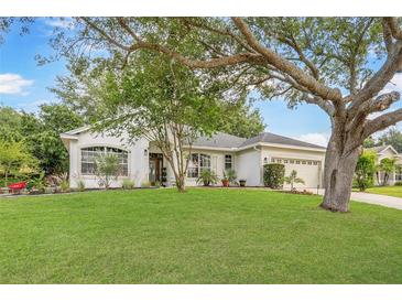 Beautiful single-story home with a lush lawn and mature trees offering great curb appeal at 13332 Via Roma Cir, Clermont, FL 34711