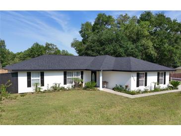 Charming single-story home featuring a well-manicured lawn and freshly painted exterior at 14350 Se 36Th Ave, Summerfield, FL 34491
