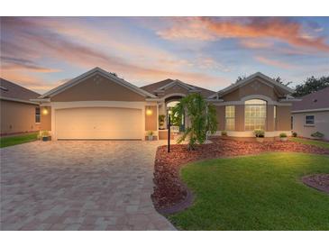 Charming single-story home boasts a well-manicured lawn, brick driveway, and attached two-car garage at 1972 Palo Alto Ave, The Villages, FL 32159