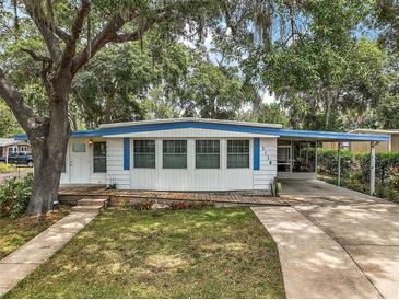 Charming single-story home with a wooden deck and a covered carport, framed by mature trees and a green lawn at 2110 Oak Cir, Mount Dora, FL 32757