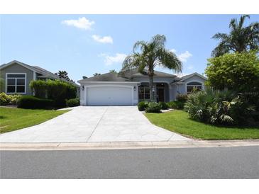 Charming single-story home featuring a spacious driveway, lush landscaping, and a welcoming two-car garage at 2120 Willow Grove Way, The Villages, FL 32162