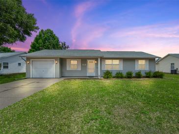 Charming single-story home features a well-manicured lawn, attached garage, and neutral-colored exterior at 2242 Orkney Dr, Leesburg, FL 34788
