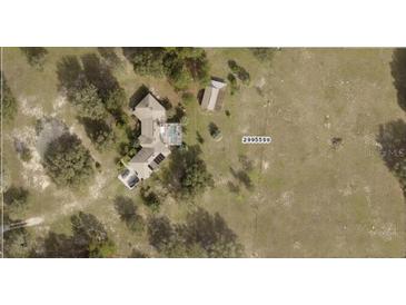 Aerial view of a home with pool and sun panels, situated on a large property with mature trees at 23130 Brouwertown Rd, Howey In The Hills, FL 34737