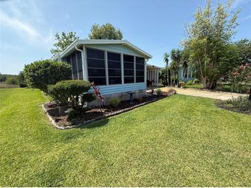 Charming home featuring a sunroom, lush landscaping, and a well-manicured lawn at 24841 Pine Hl, Leesburg, FL 34748