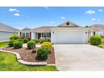 Charming single-story home with well-manicured landscaping and a two-car garage on a sunny day at 3118 Sweetgum St, The Villages, FL 32163
