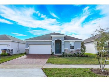 Charming single-story home featuring a well-manicured lawn, brick driveway, and an attached two-car garage at 5006 Abigail Dr, Lake Wales, FL 33859
