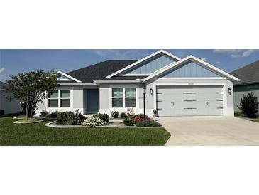 Charming single-story home with a manicured lawn, gray exterior paint, and a two-car garage at 6633 Holovak Ter, The Villages, FL 34762