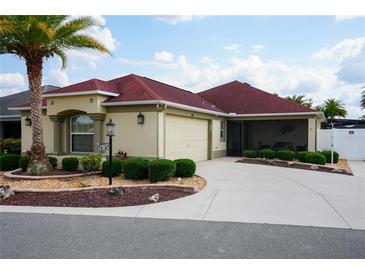 Charming home featuring a well-manicured lawn, a vibrant palm tree, and a red roof at 664 Mission Hills Trl, The Villages, FL 32162