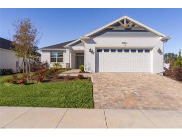 Charming single-Gathering home featuring a well-manicured lawn and a brick paved driveway leading to a two-car garage at 12624 Ne 49Th Dr, Oxford, FL 34484