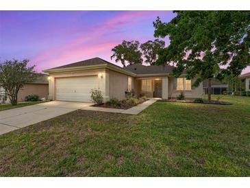 Charming single-story home featuring a well-manicured lawn, two-car garage, and landscaped flowerbeds at 12687 Se 90Th Ter, Summerfield, FL 34491