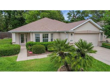 Charming single-story home with well-maintained landscaping, complemented by a two-car garage and inviting walkway at 13050 Se 89Th Cir, Summerfield, FL 34491