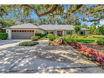 Inviting single-story home featuring mature landscaping, a two-car garage, and a charming red front door at 1341 W Lakeshore Dr, Clermont, FL 34711