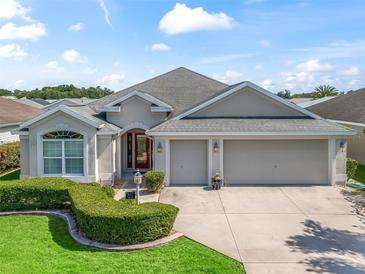 Charming single-story home boasts a three-car garage, lush landscaping, and a welcoming front entrance at 1642 Pennecamp Dr, The Villages, FL 32162