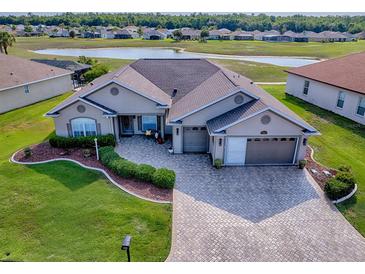 Beautiful home featuring a manicured lawn, paver driveway, and stunning water views at 17563 Se 122Nd Ter, Summerfield, FL 34491