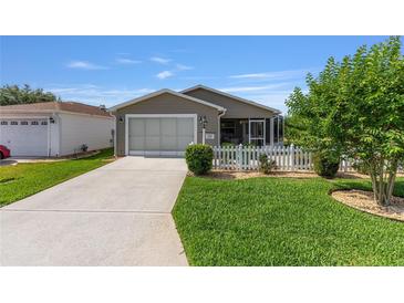 Charming home with a one-car garage, a screened-in porch, and a manicured front lawn at 2348 Riley Rd, The Villages, FL 32162