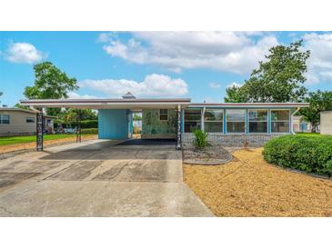 Charming single-story home featuring a covered parking area and a beautifully landscaped front yard with blue accents at 2706 Vindale Rd, Tavares, FL 32778