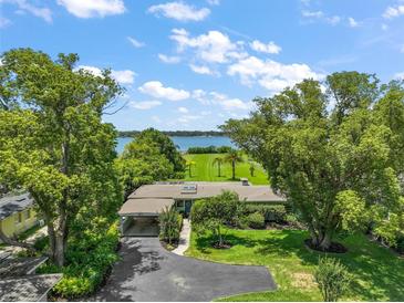 Beautiful waterfront property featuring lush landscaping, mature trees, and an expansive lawn leading to the water at 33637 E Lake Joanna Dr, Eustis, FL 32736