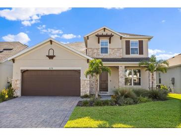 Charming two-story home featuring stone accents, a paved driveway, and meticulously landscaped front yard at 674 Anna Ridge Rd, Minneola, FL 34715