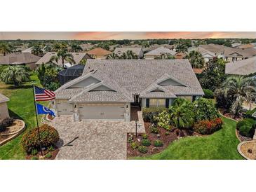 Charming home with a 3-car garage, meticulously landscaped yard, and brick-paved driveway in a lush community at 1053 Alcove Loop, The Villages, FL 32162