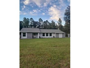 Charming single-story home featuring a well-maintained lawn and quaint front entrance at 17873 E Highway 40, Silver Springs, FL 34488