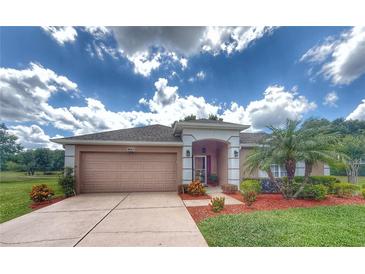 Charming single-story home boasts a well-manicured lawn, tan color scheme, and inviting front entry at 1930 Farmington Ct, Clermont, FL 34711