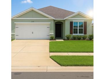Inviting single-story home featuring a two-car garage, a well-manicured lawn, and charming architectural details at 2106 Elio Ridge Dr, Zellwood, FL 32798