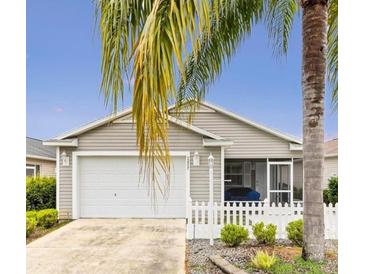 Charming single-story home featuring a white picket fence, a two-car garage, and a screened in front porch at 2457 Upton St, The Villages, FL 32163