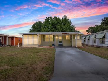 Charming home featuring an enclosed porch and a well-maintained lawn under a beautiful sunset sky at 32521 W Golf Ct, Leesburg, FL 34748