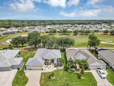 Expansive aerial view of community with lush landscaping, golf course, and single-story homes under a partly cloudy sky at 3677 Arlington Ridge Blvd, Leesburg, FL 34748
