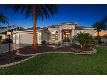 Well-manicured lawn and mature landscaping enhance this single-story home's curb appeal with elegant entry at 4033 Swaying Palm Ct, The Villages, FL 32163