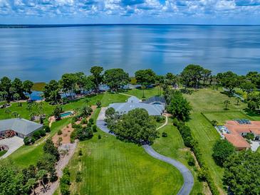 Expansive lakefront property with a well-manicured lawn, mature trees, and stunning water views at 11226 Lane Park Rd, Tavares, FL 32778