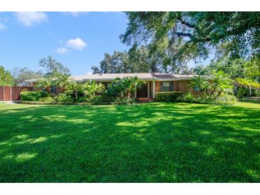 Charming single-story brick home with a manicured lawn and mature landscaping including palm trees at 15935 J And J Dr, Tavares, FL 32778