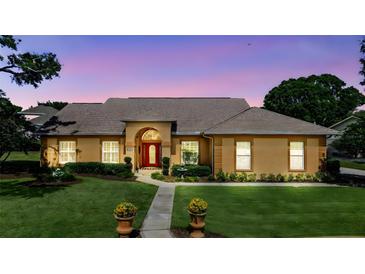 Charming exterior view of a single-story home with a red front door and well-manicured landscaping at 34021 Park Ln, Leesburg, FL 34788