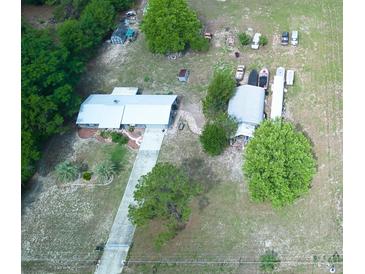 An aerial view of a cozy home with a long driveway and spacious yard, nestled among lush trees at 37149 Grays Airport, Lady Lake, FL 32159