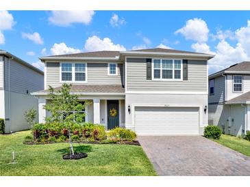 Charming two-story home with manicured lawn, brick driveway, and attached two car garage at 7627 Taormina Way, Clermont, FL 34714