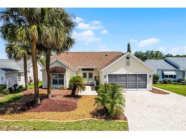 Charming single-story home with paver driveway, palm trees, and well-maintained landscaping at 815 Cortez Ave, Lady Lake, FL 32159