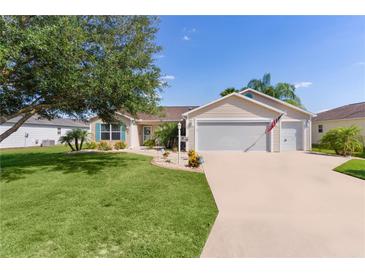 Charming single-story home with a well-manicured lawn, mature tree, and two-car garage at 898 Abaco Path, The Villages, FL 32163
