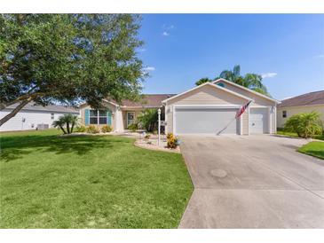 Charming single-story home featuring a well-manicured lawn, mature tree, and attached two-car garage at 898 Abaco Path, The Villages, FL 32163