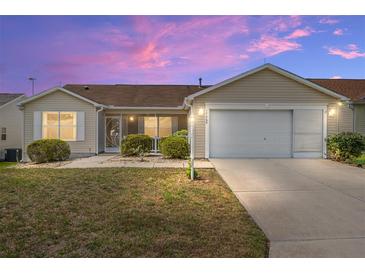 Charming single-story home featuring manicured landscaping and a two-car garage at sunset at 17068 Se 96Th Chapelwood Cir, The Villages, FL 32162