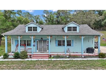 Charming home with dormer windows, front porch with decorated pillars and a light blue exterior at 19703 Lake Lincoln Ln, Eustis, FL 32736