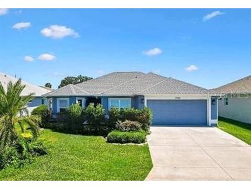 Charming single-story home featuring a two-car garage and well-manicured front lawn under a blue sky at 2160 Biller Cir, The Villages, FL 32163