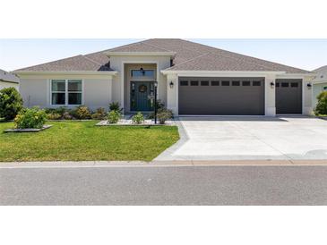 Charming home featuring a well-manicured lawn, a two-car garage, and decorative front door with a wreath at 2988 Sentell St, The Villages, FL 32163