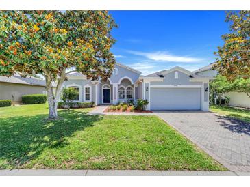 Charming one-story home featuring a well-manicured lawn, mature tree, and a two-car garage on a sunny day at 4716 Block Island Ln, Clermont, FL 34714