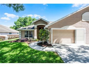 Charming single-story home featuring a well-manicured lawn, tasteful landscaping, and an attached two-car garage at 8527 Firestone Cir, Clermont, FL 34711