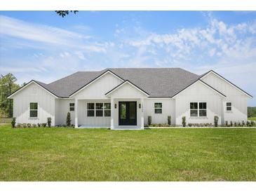Modern farmhouse exterior showcasing a well-manicured lawn and black trimmed windows and doors at 12565 Cynthia Ln, Clermont, FL 34715