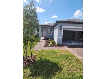 Charming single-Gathering home featuring a well-maintained lawn, brick driveway, and attached two-car garage at 1808 Carnostie Rd, Winter Haven, FL 33884