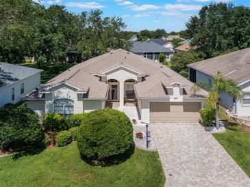 Inviting one-story home with a manicured lawn, brick driveway, and mature landscaping, perfect for curb appeal at 25243 River Crest Dr, Leesburg, FL 34748