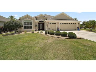 Charming single-story home featuring a well-manicured lawn, mature landscaping, and a two-car garage at 3411 Eisenhower Way, The Villages, FL 32163