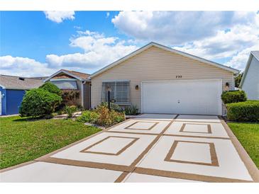 Charming single-story home with well-maintained landscaping and decorative driveway at 735 Palma Dr, Lady Lake, FL 32159