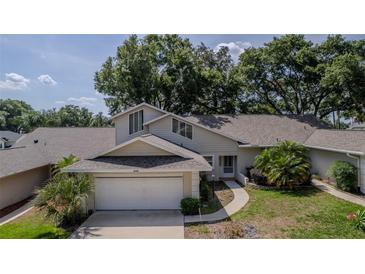 Charming home featuring a two-car garage, a well-manicured lawn, and mature trees offering plenty of shade at 8705 Village Green Blvd, Clermont, FL 34711